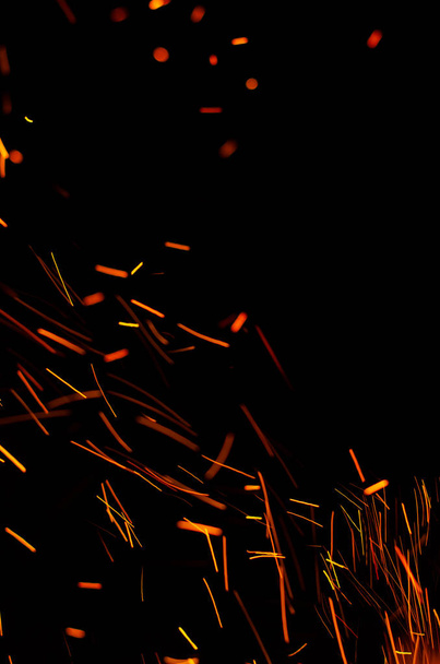 Chispas rojas ardientes volando sobre un fondo negro. Ardientes partículas brillantes volando en el cielo nocturno. Fondo abstracto
 - Foto, Imagen