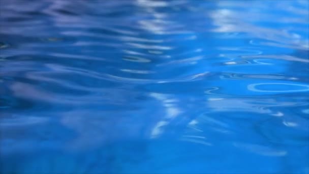 Καθαρό μπλε νερό στην πισίνα με φωτεινές αντανακλάσεις. Αργή κίνηση. - Πλάνα, βίντεο