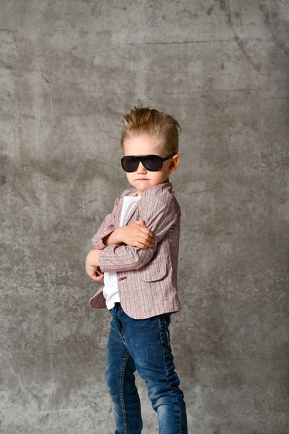 Зображення веселого збудженого маленького хлопчика, який стоїть ізольовано над бетонною стіною
. - Фото, зображення