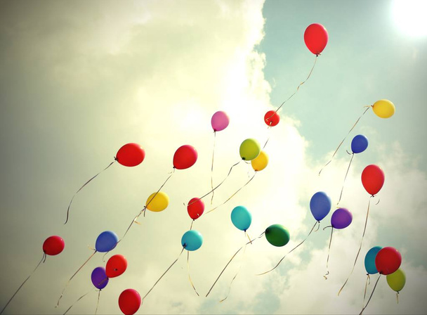 many colored balloons fly to the light on the blue sky - Photo, Image