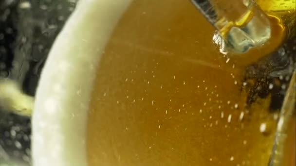 beer is poured into a glass from a bottle on a dark background foam flows down a glass - Materiał filmowy, wideo