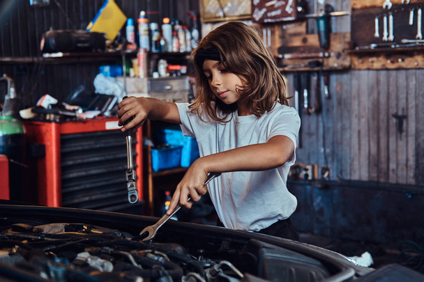 Porträt eines netten kleinen Mädchens in der Werkstatt des Autoservice - Foto, Bild