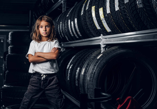 Πορτρέτο ενός κοριτσιού σε σκοτεινό χώρο αποθήκευσης ελαστικών - Φωτογραφία, εικόνα