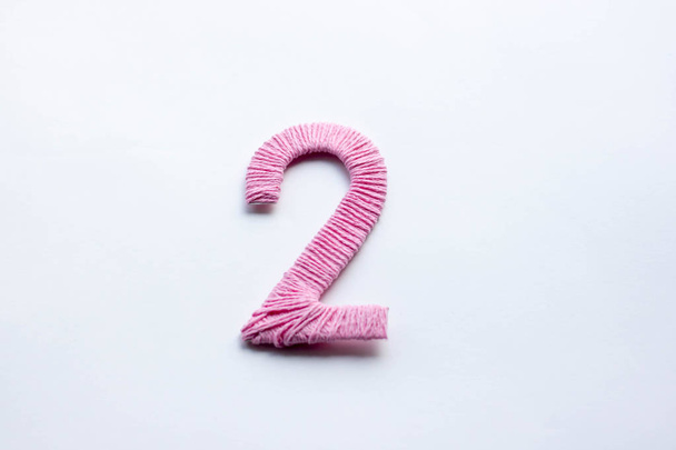 Νούμερο δύο, διακοσμητικό ψηφίο σε ροζ επιφάνεια. - Φωτογραφία, εικόνα
