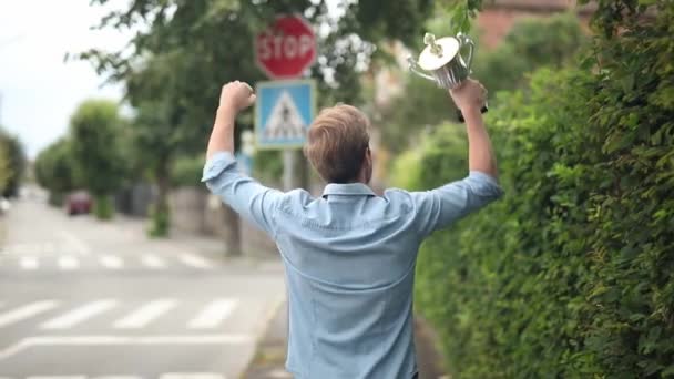 Achteraanzicht van een vrolijke winnende man met handen in de lucht die het succes viert en zijn Big Trophy Award - Video