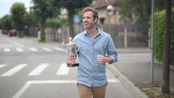 happy cheerful young casual man celebrates his big win in the street with hands in the air - Footage, Video