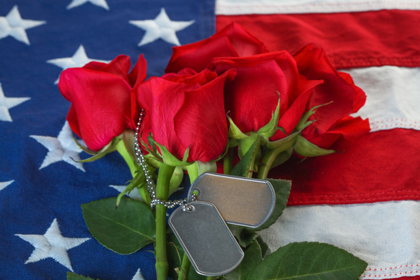 Αμερικανική σημαία με τριαντάφυλλα και λευκές στρατιωτικές ετικέτες σκύλων - Φωτογραφία, εικόνα