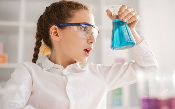 Shocked girl with chemical liquid in classroom - Zdjęcie, obraz