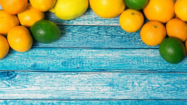 Citrus fruits. Oranges, tangerines, limes and lemons. Over wooden table background with copy space - 写真・画像