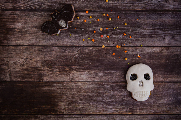 Biscoito de gengibre pintado à mão assustador crânio de Halloween com polvilhas coloridas no fundo de madeira. Vista superior
 - Foto, Imagem