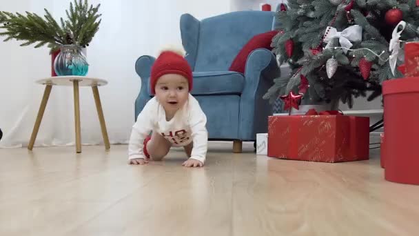 Cute little baby in christmas clothes crawling on the wooden floor to her kneeling mother with beautiful presents - Záběry, video