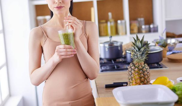 Young woman with glass of tasty healthy smoothie at table in kitchen - 写真・画像