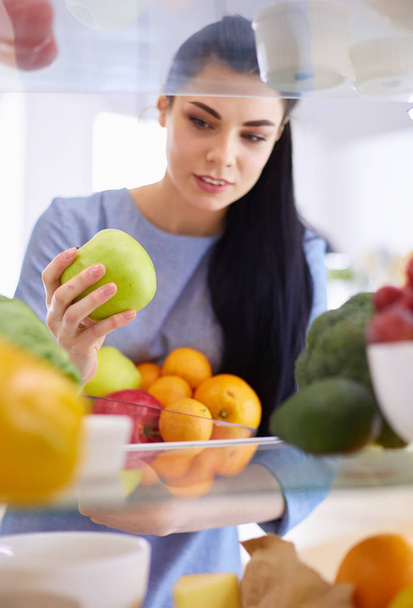 Smiling woman taking a fresh fruit out of the fridge, healthy food concept - Zdjęcie, obraz