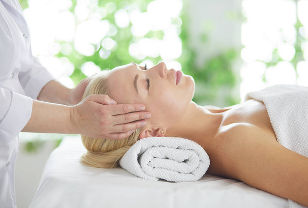 Beautiful woman doing facial massage in a spa salon. - 写真・画像