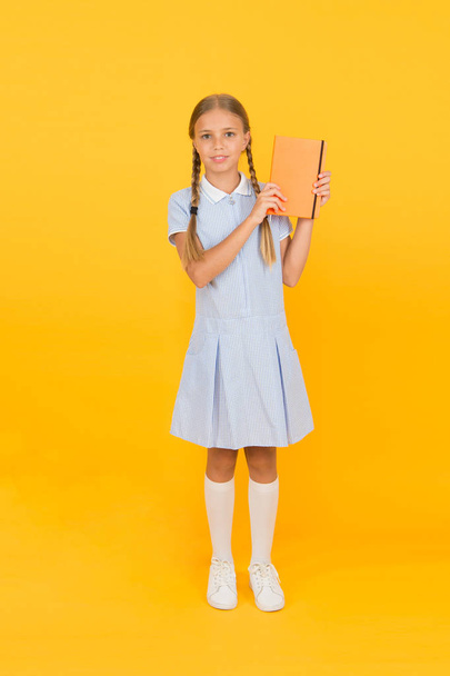 Diary for girls concept. happy little girl in retro uniform. vintage kid fashion. back to school. girl hold workbook or notepad. encyclopedia book for children. small girl love literature. old school - Zdjęcie, obraz