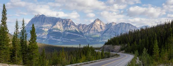Scenic road in the Canadian Rockies during a vibrant sunny and cloudy summer morning. Taken in Icefields Parkway, Banff National Park, Alberta, Canada. - Photo, image