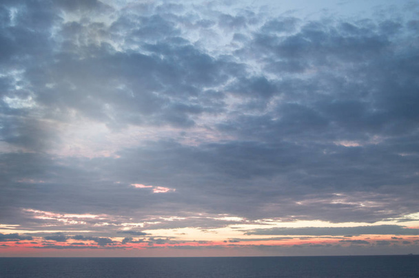 Rauhallinen auringonlasku tai auringonnousu Välimeren yllä, aurinko paistaa pehmeiden sinisten ja vaaleanpunaisten pilvien läpi
 - Valokuva, kuva