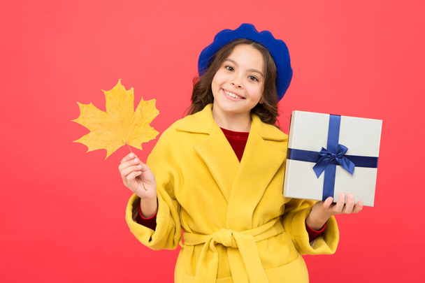 Autumn offer. Little girl and gift box. Kid cute face hold maple leaf. Seasonal sale. Child with autumn leaf received present. Autumn shopping. Black friday. Small girl fall outfit red background - Photo, image