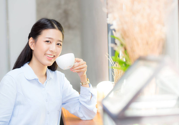 Красива молода азіатка п'є каву і посміхається в морі
 - Фото, зображення
