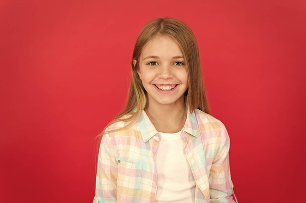 Girl joyful smiling face over red background. Emotional kid happy smiling face. Cheerful adorable girl smiling. Positive and optimistic. Cheerful mood. Sincere emotions. Brilliant smile concept - Fotografie, Obrázek