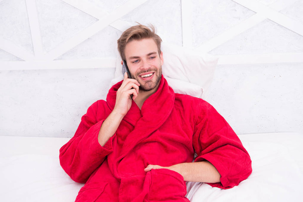Modern life is impossible without cellular communication. Modern guy talking on smartphone in bed. Handsome man making a call with modern mobile phone from home. Modern technology for everyday life - Foto, Imagem