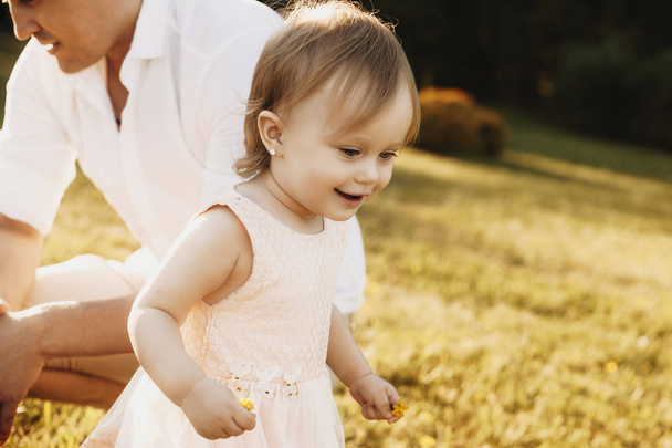 Nahaufnahme eines schönen kleinen Mädchens, das Spaß dabei hat, draußen zu lächeln. Kind läuft und lächelt im Hinterhof . - Foto, Bild