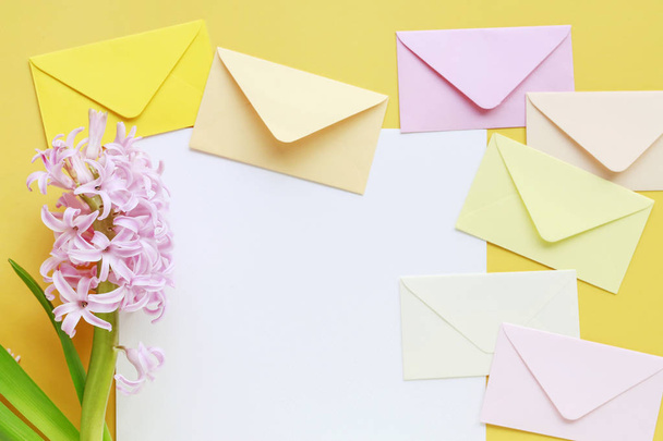Colorful envelopes and hyacinth flowers on yellow background - Foto, afbeelding