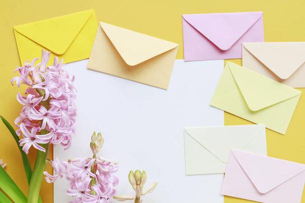 Colorful envelopes and hyacinth flowers on yellow background - Fotografie, Obrázek
