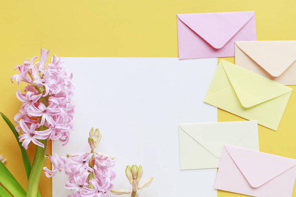 Colorful envelopes and hyacinth flowers on yellow background - Fotó, kép