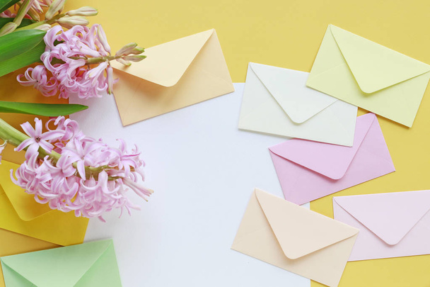 Colorful envelopes and hyacinth flowers on yellow background - Fotografie, Obrázek