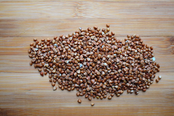 Buckwheat on wooden cutting board. Concept of natural healthy dietary nutrition. - Φωτογραφία, εικόνα