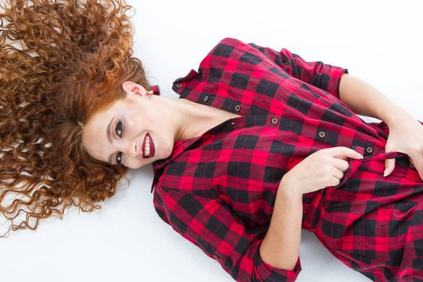 young girl with red hair lies on a white background - Foto, Imagen