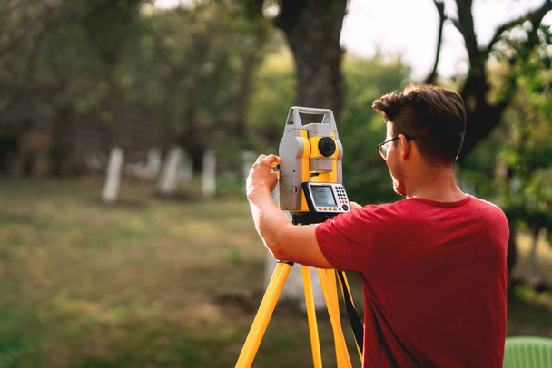 Portrait of professional surveyor engineer measuring and working with total station - Foto, immagini