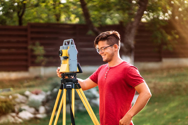 Portrait of surveyor engineer using equipment with theodolite and total station at a construction site - Fotoğraf, Görsel