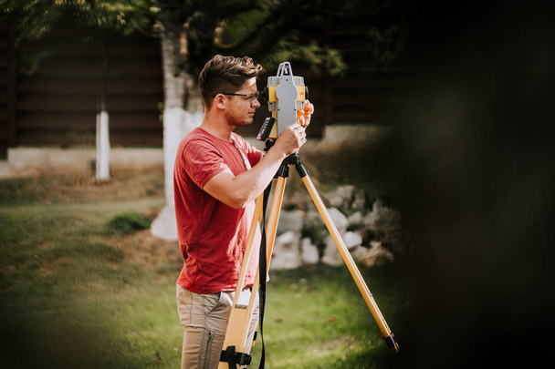 Portrait of surveyor engineer working with total station theodolite and gps system on construction site - Foto, imagen