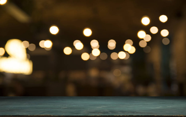 Prázdný dřevěný stůl nahoře na světle vyostřené zlaté bokeh Café Restaurant na tmavém pozadí - Fotografie, Obrázek