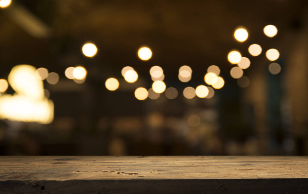 暗い背景にカフェレストランのぼかしライトゴールドボケに空の木製テーブルトップ - 写真・画像