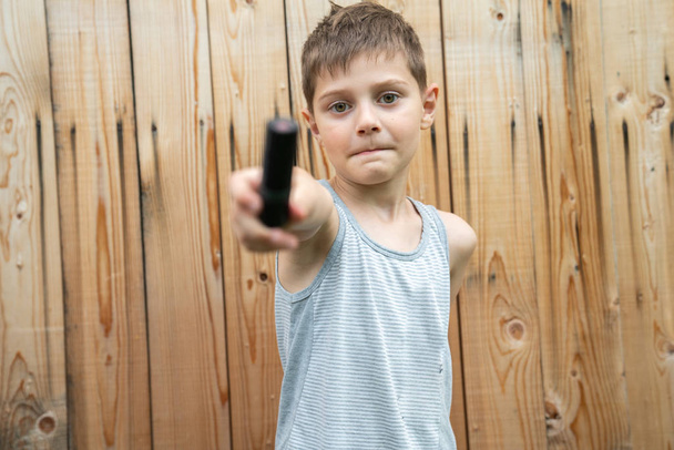 halblanges Foto eines kleinen Jungen in grauem T-Shirt, das mit schwarzem Schlauch isoliert über einer Holzwand spielt - Foto, Bild