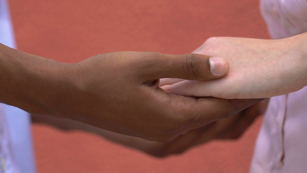 Afroamerykanin mężczyzna dotykając kaukaskie dziewczyny ręce, delikatne stosunki - Materiał filmowy, wideo
