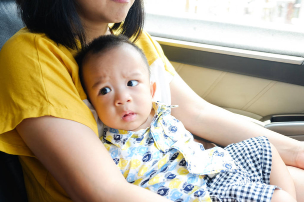 Aziatische jongen reizen met moeder zittend op schoot in de auto - Foto, afbeelding