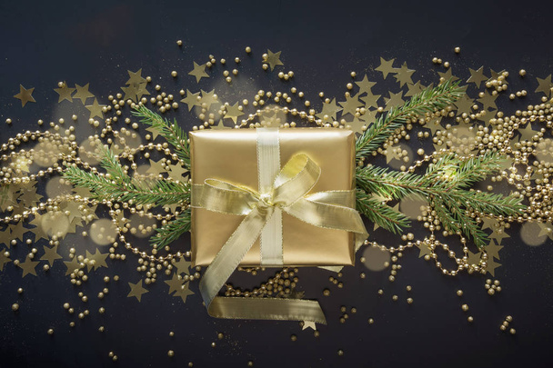 Роскошная золотая подарочная коробка с золотой лентой на светлом черном фоне. Рождественский подарок. Плоский лежал. Вид сверху. Xmas
. - Фото, изображение