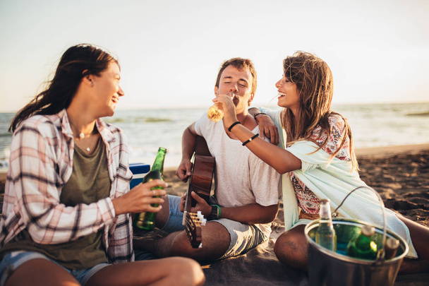 Szczęśliwi przyjaciele imprezują na plaży z drinkami - Zdjęcie, obraz