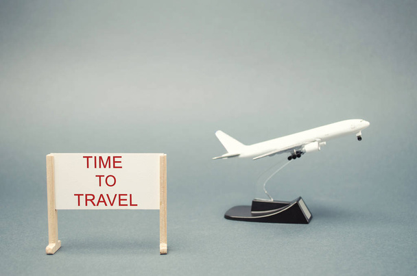A poster with the words Time to travel and a miniature airplane. The concept of planning a summer or winter vacation. Family rest. Hot tours. Available offers. Aircraft. Plane - Fotografie, Obrázek
