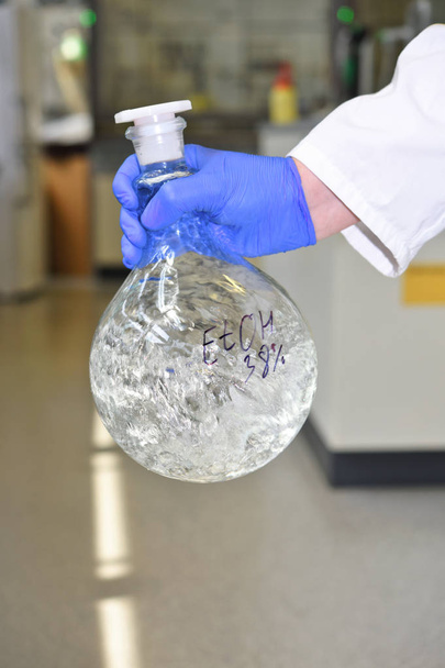 Un químico mezcla un frasco grande con líquido transparente en el laboratorio
 - Foto, Imagen