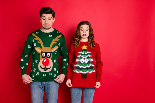 What disgust. Portrait of frustrated two brunette haired students stare at deer christmas tree design jumper displeased wear stylish trendy jeans denim isolated over red color background - Photo, image