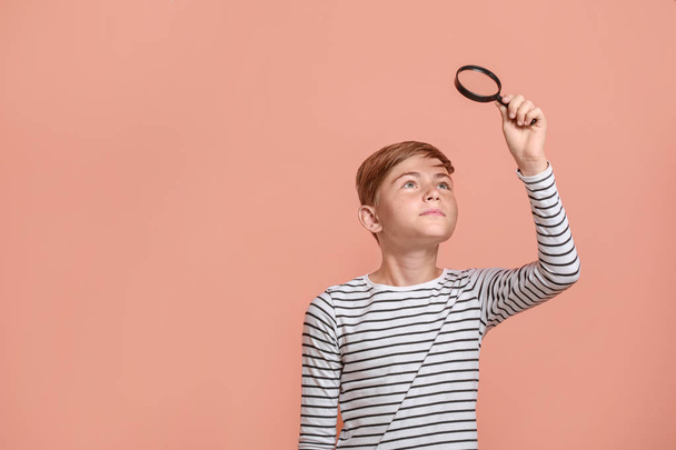 Little boy with magnifying glass on color background - Foto, afbeelding
