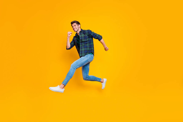 Full length body size side profile photo of cheerful positive funny trendy guy wearing jeans denim hurrying jumping up to sales isolated over vivid color yellow background - Foto, imagen
