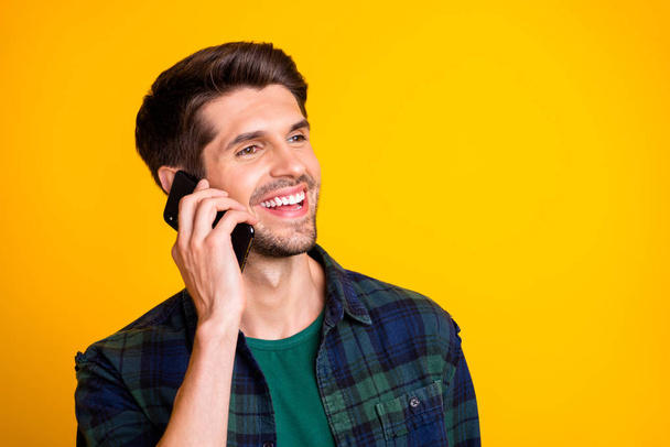 Closeup photo of nice guy holding telephone near ear speaking with best friend casual checkered shirt isolated yellow color background - Zdjęcie, obraz