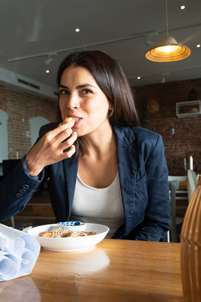 Young beautiful brunette woman biting food in an Asian restaurant - Photo, image