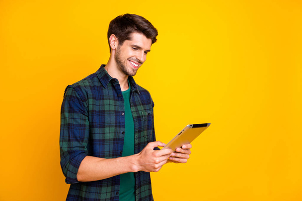 Photo of cool guy with e-reader in hands watching online lecture wear casual checkered shirt isolated yellow color background - Фото, изображение